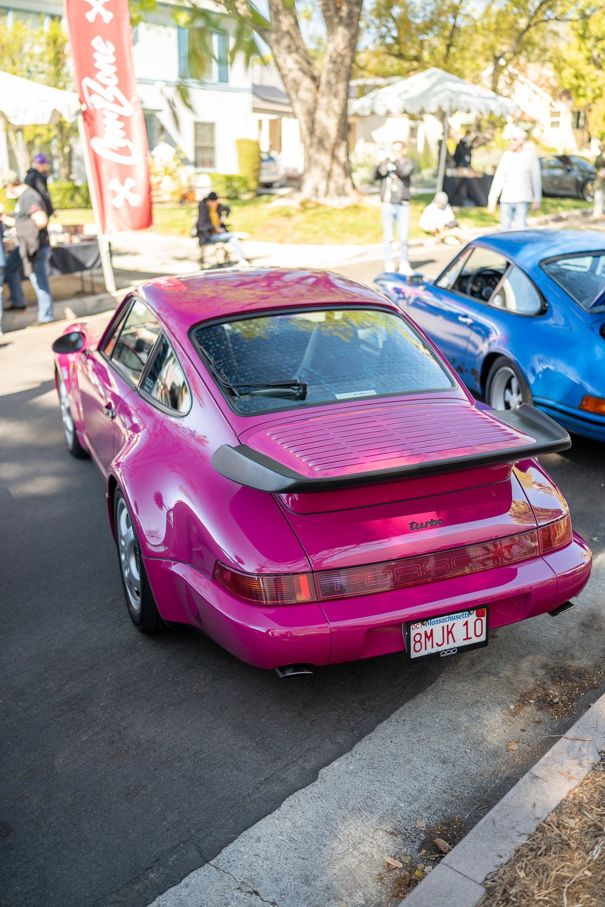 Pink 964 Turbo Porsche with black trim and spoiler at a car show in Los Angeles.