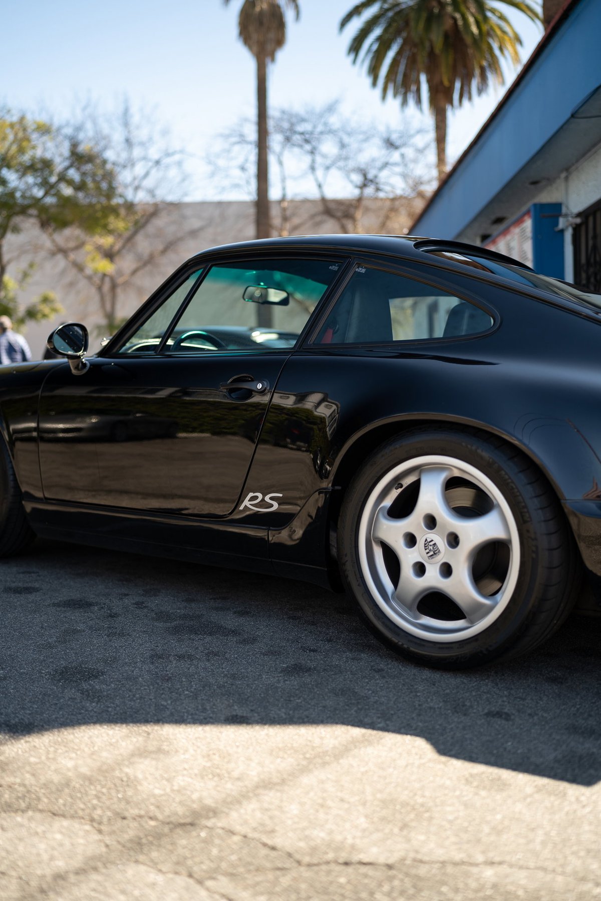 Black Porsche 911 RS with silver five-spoke rims and subtle "RS" badging.