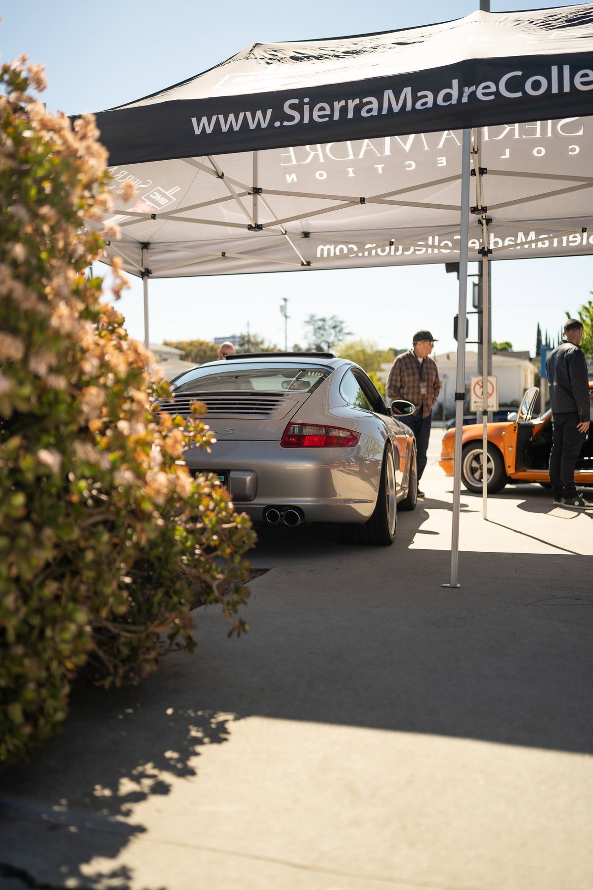 Silver Porsche 911 coupe with dual exhaust tips, parked under a tent.