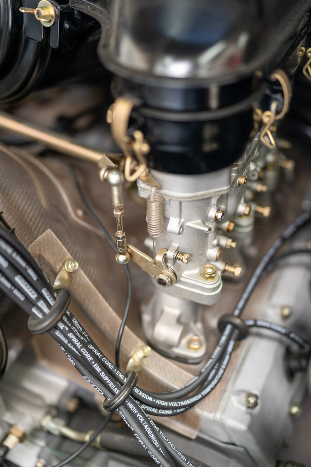 Close-up of vintage Porsche 911 engine carburetor and spark plug wires.
