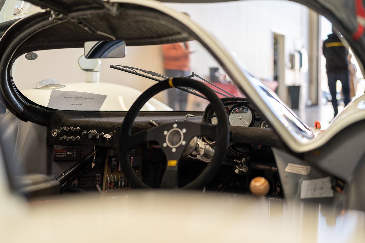 Vintage Porsche interior featuring a classic steering wheel, analog gauges, and a wooden shift knob.