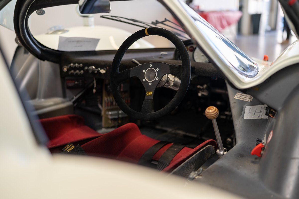 Vintage race car interior with OMP steering wheel and red racing seats.