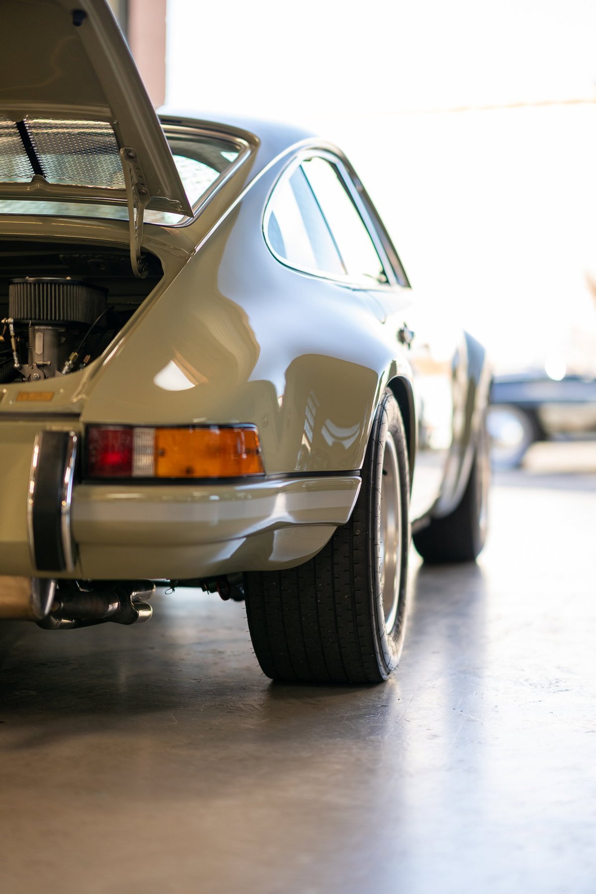 Light green 1973 Porsche 911 Carrera RS rear-quarter view, engine exposed, Fuchs rims.