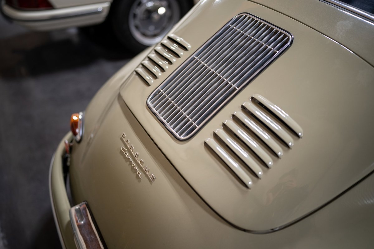 Close-up of a tan Porsche 356 engine lid with chrome vents and badging.