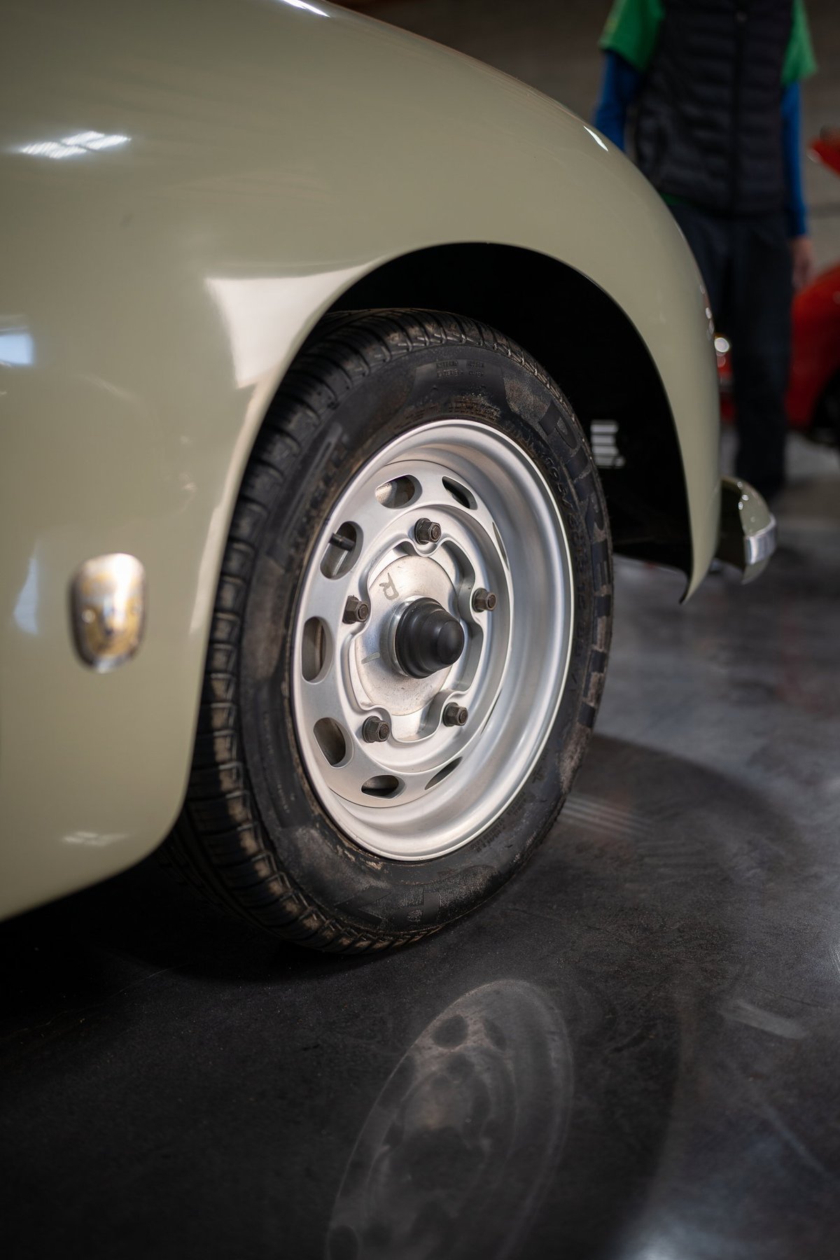 Vintage Porsche 356 in pale green, showing a polished aluminum rim and tire detail.
