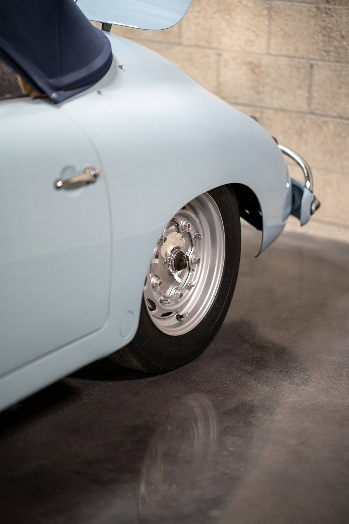 Light blue 1950s Porsche 356 Speedster rear wheel with polished aluminum rims.