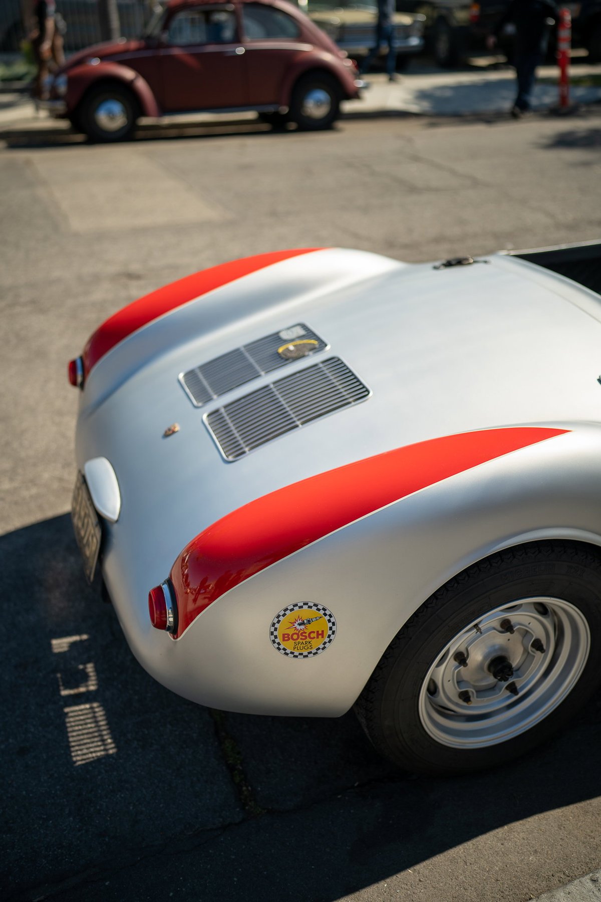 Close-up of a silver Porsche 550 Spyder with red trim and a Bosch decal on the fender.