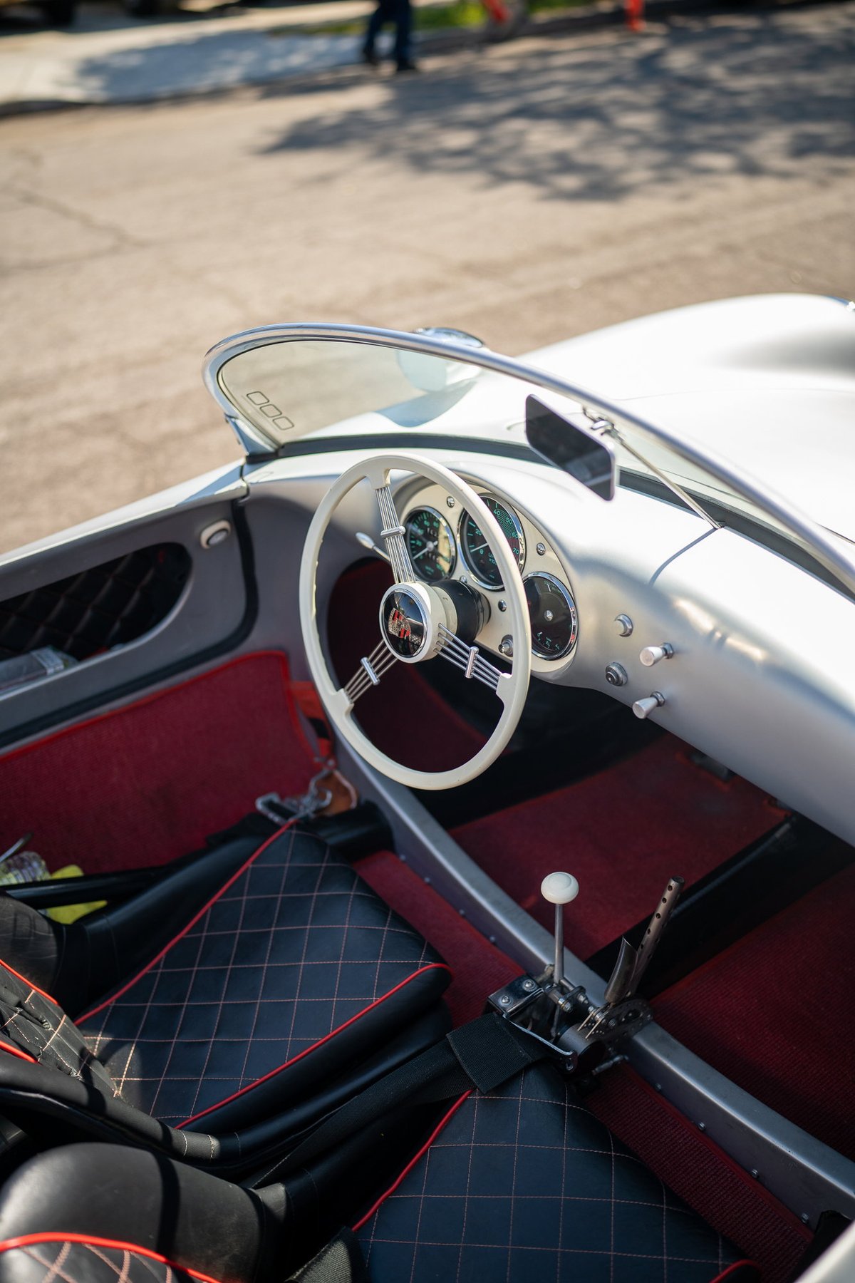 Silver Porsche 356 Speedster interior with red carpeting and diamond-stitched seats.