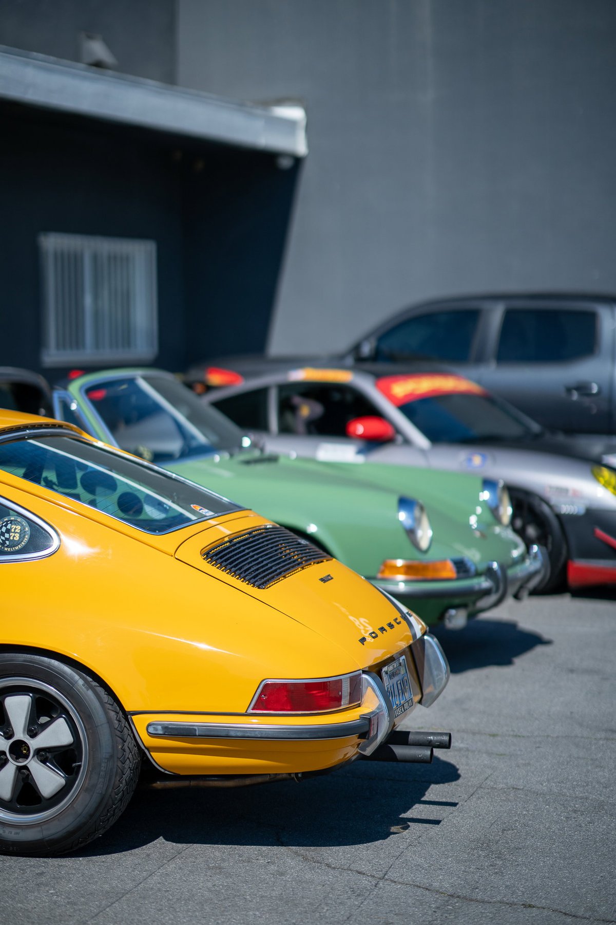 Rear view of a yellow Porsche 911 with Fuchs rims and chrome trim. Lit Show LA 2022.