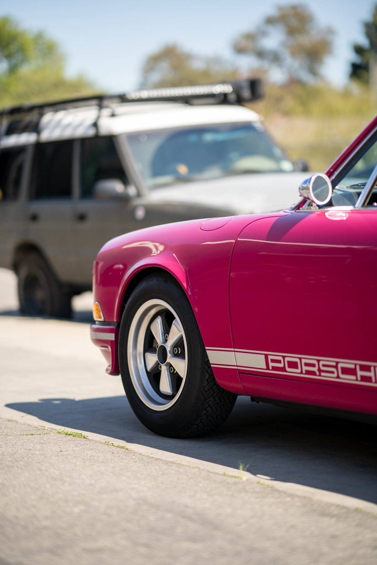 Pink Porsche with a white stripe livery and classic five-spoke rims.
