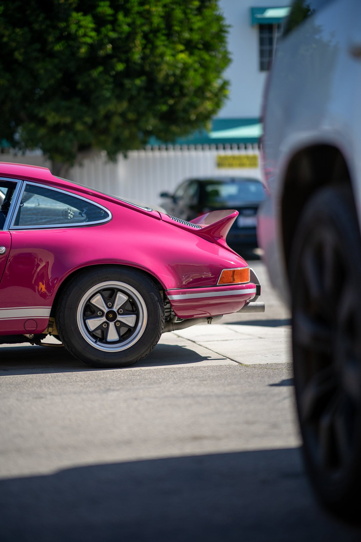 Pink Porsche 911 with ducktail spoiler and Fuchs wheels.