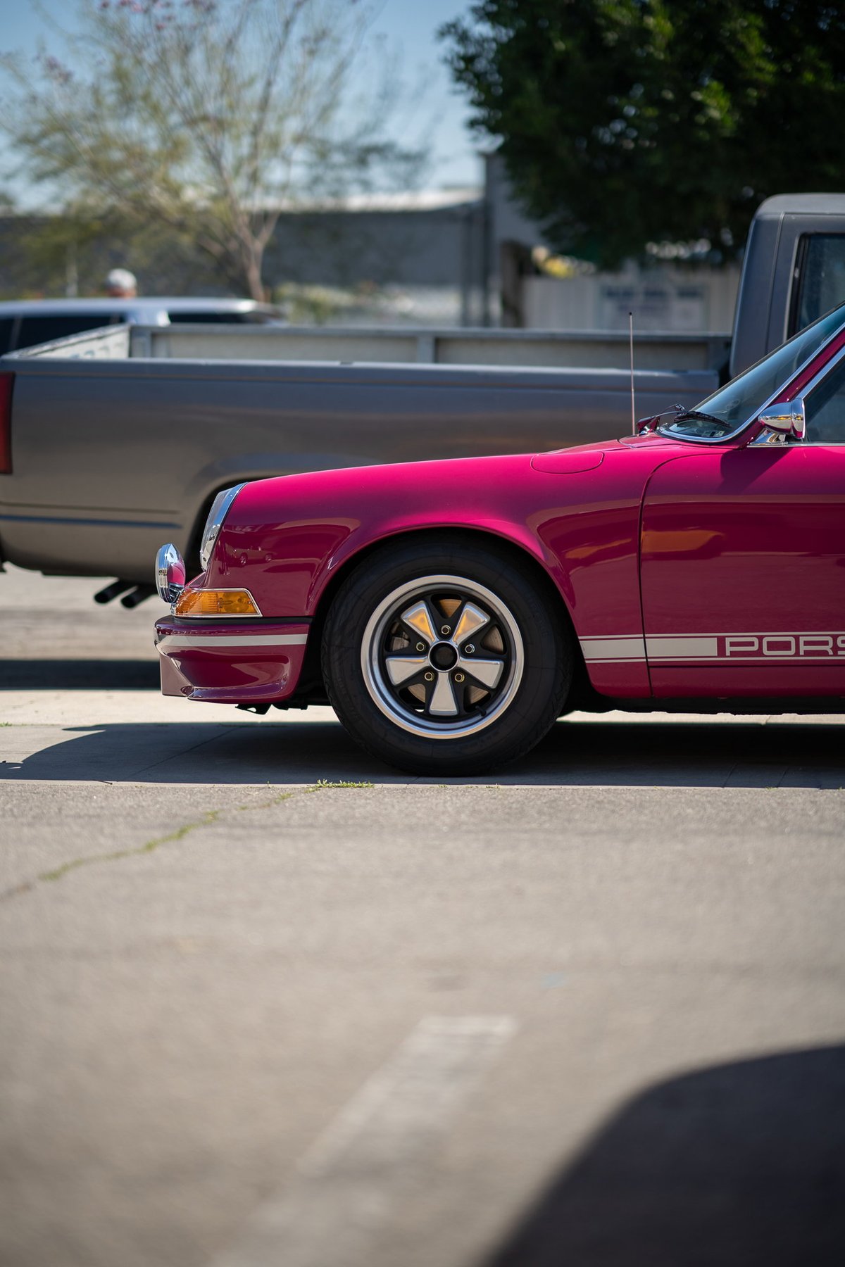 Pink 1970s Porsche 911 with classic Fuchs rims and silver side livery.