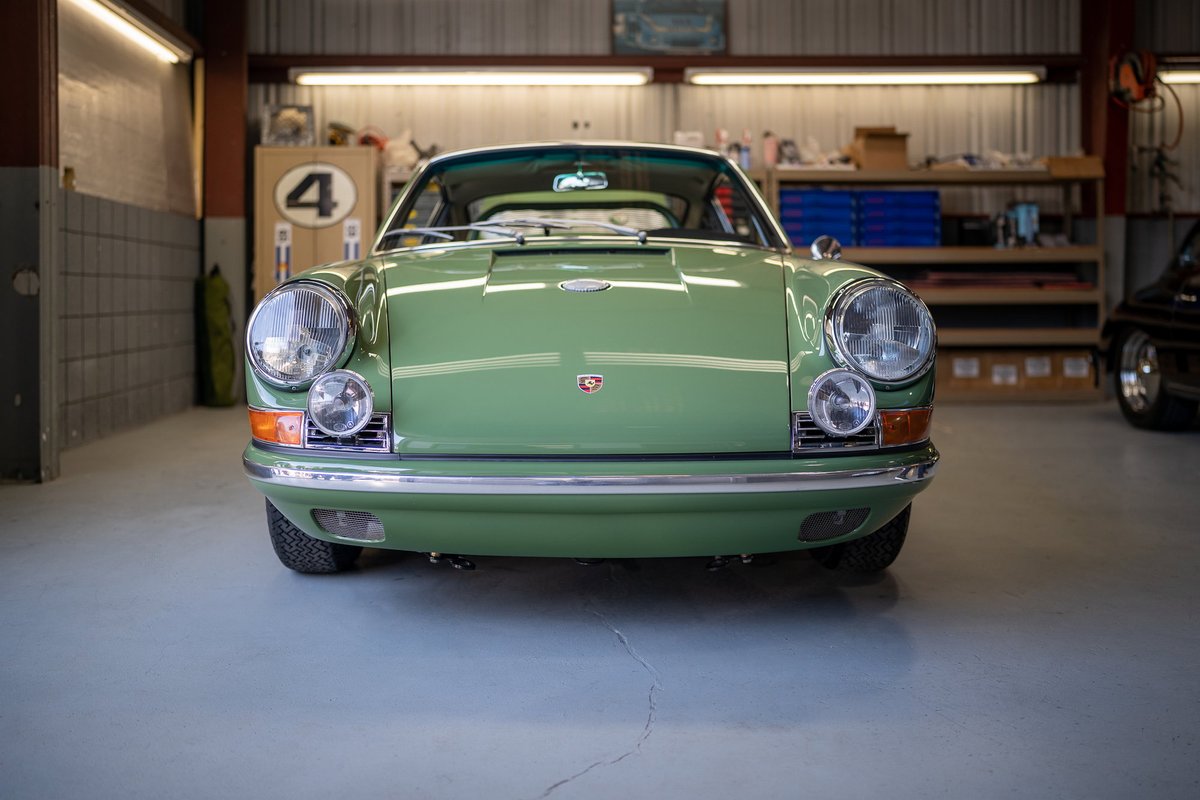 Front view of a green Porsche 911 in a garage.