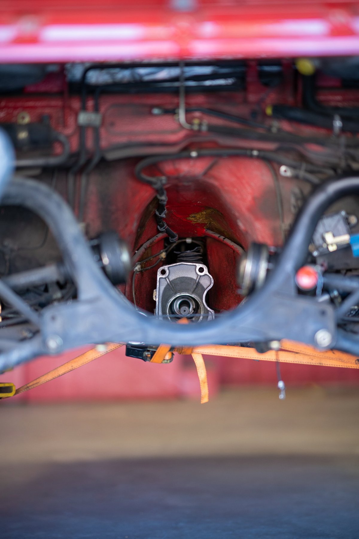 Red Porsche 911 drivetrain. Transmission and suspension components visible.
