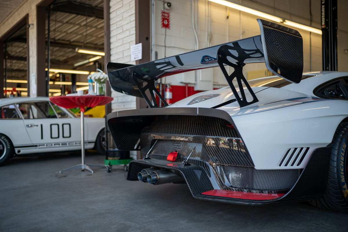 White race car with a large carbon fiber wing and diffuser.