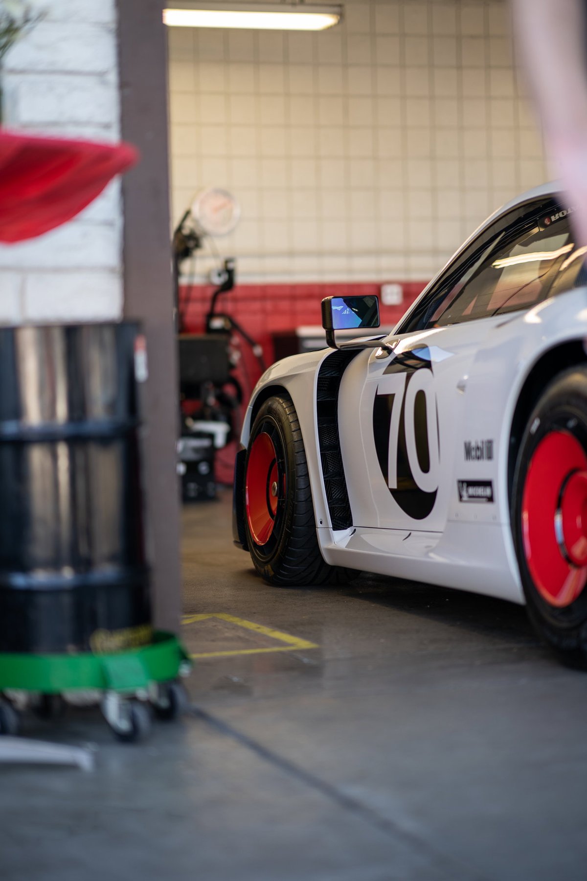 White Porsche 911 with racing livery, black '70' graphics and red rims.