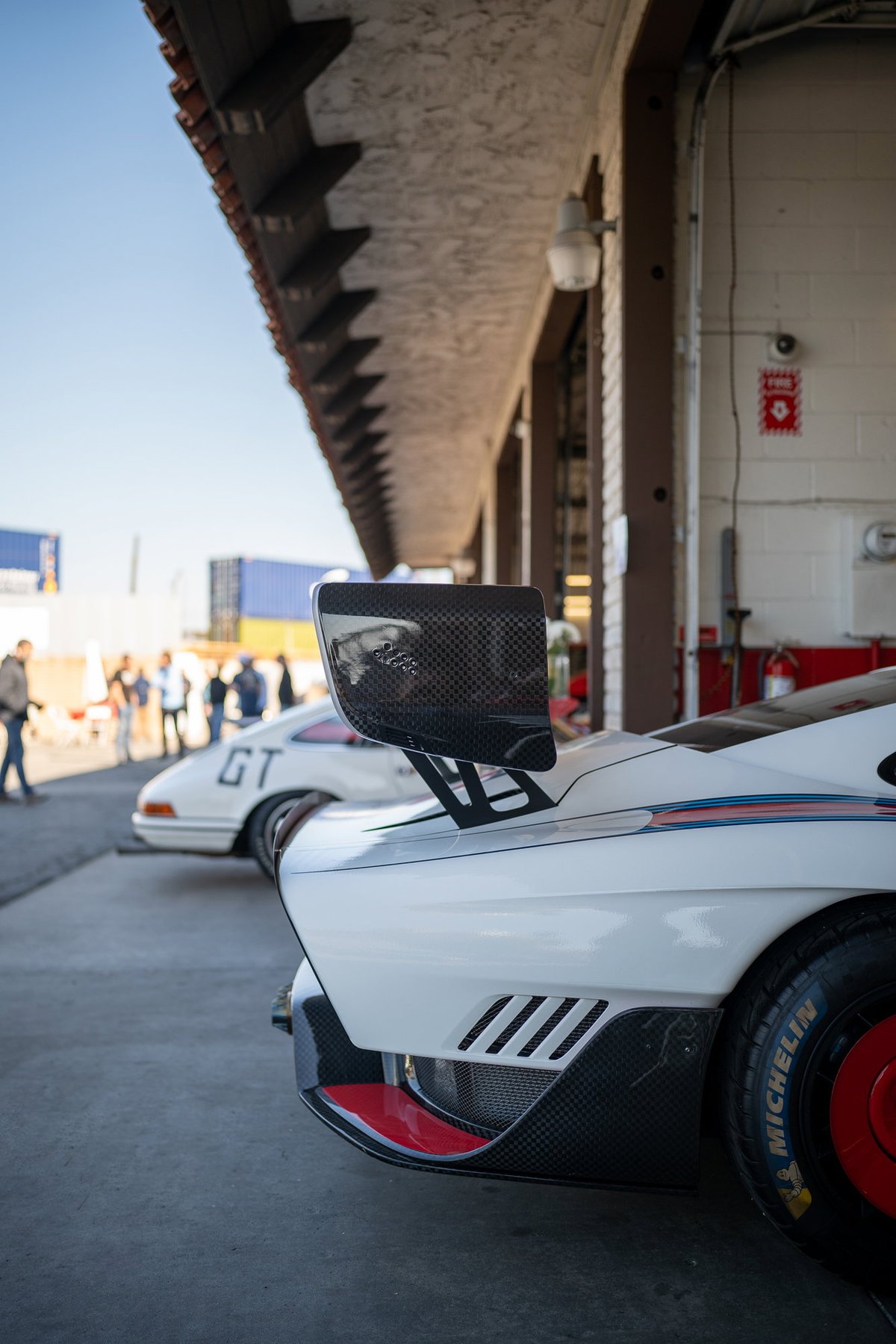 Close-up of a white Porsche 911 GT race car rear, with carbon fiber wing and red trim.