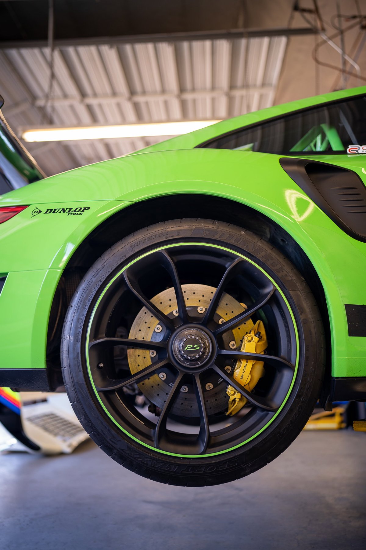 Close-up of a lime green Porsche 911 GT3 RS wheel with yellow calipers, on Dunlop tires.