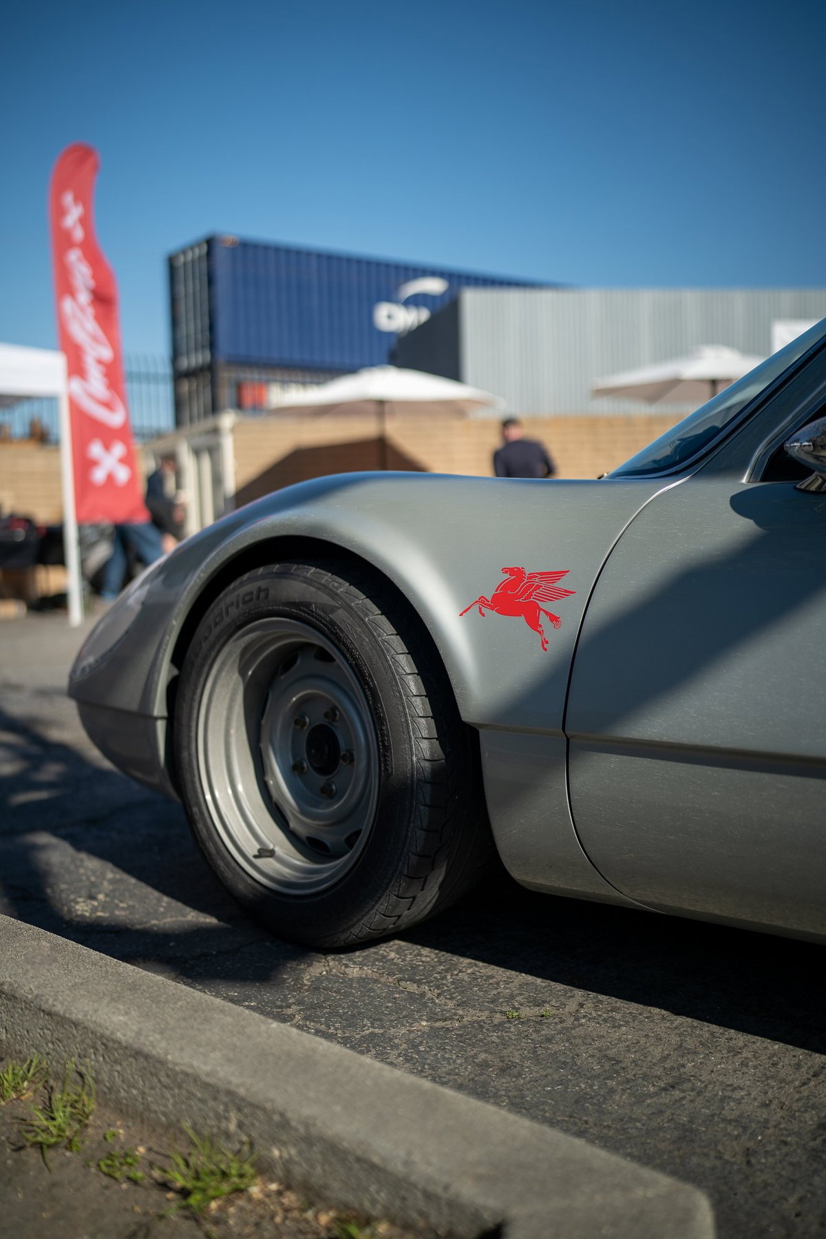 A silver Porsche 914 with a red Pegasus livery on the fender.
