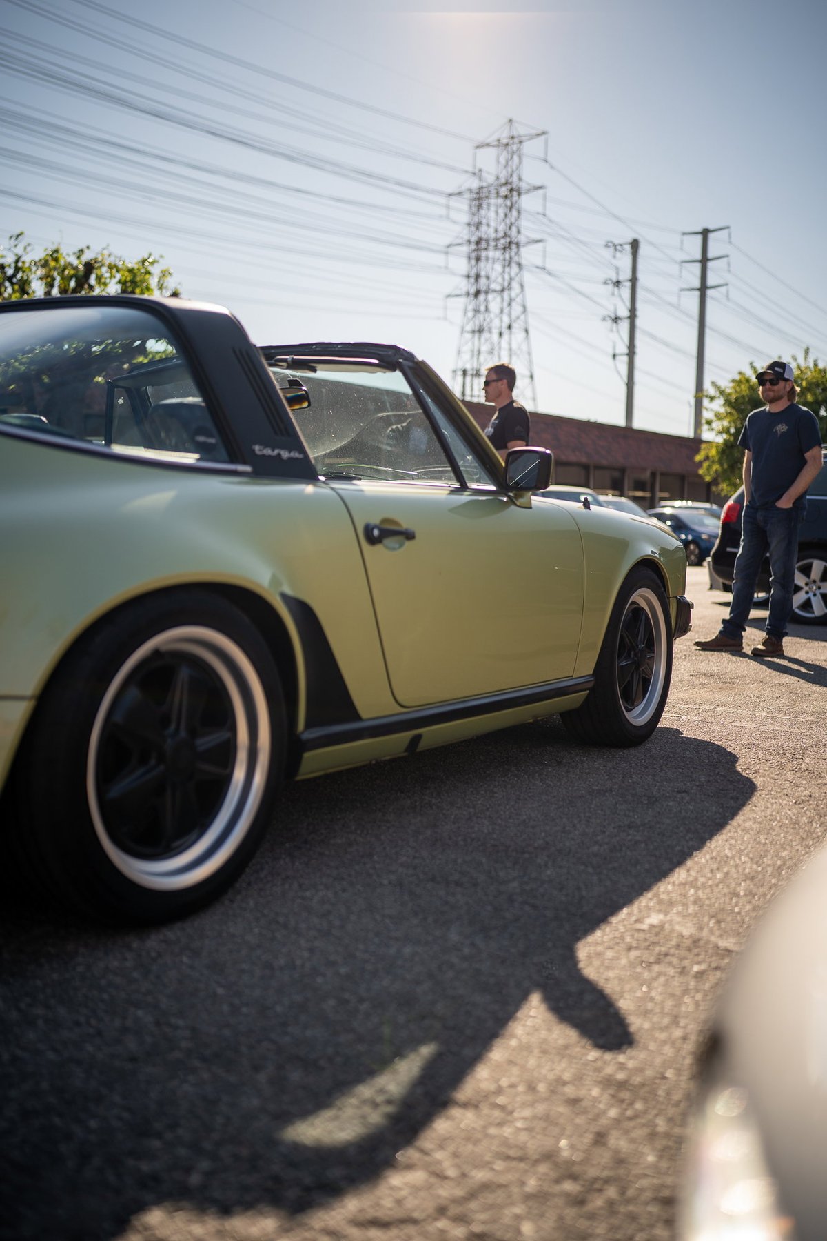 A pale yellow 1970s Porsche 911 Targa with black trim and Fuchs wheels.