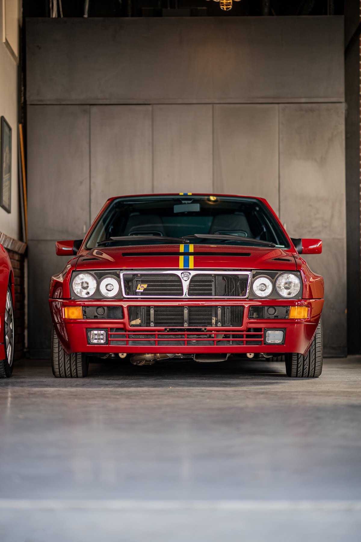 Front view of a red Lancia Delta Integrale with rally livery stripes.
