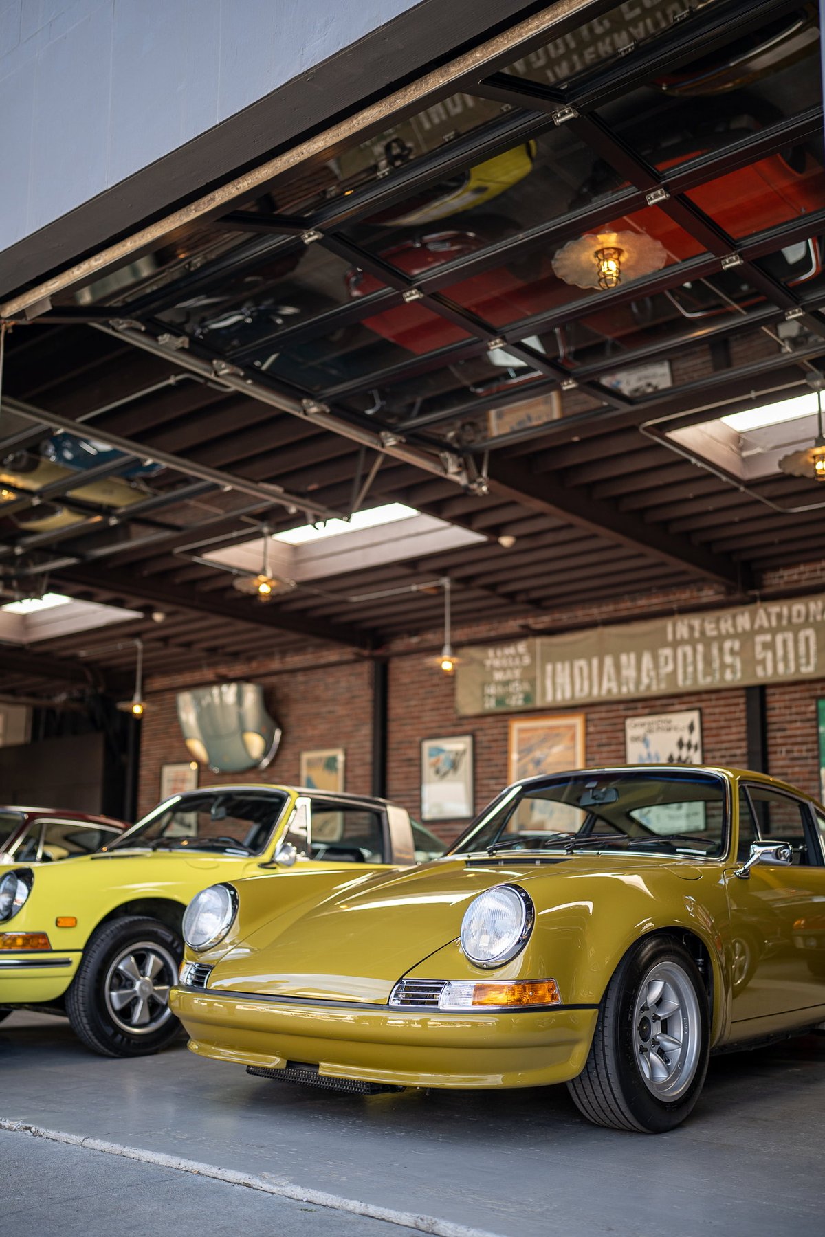 Yellow Porsche 911 S Targa, classic rims, chrome trim, in garage.