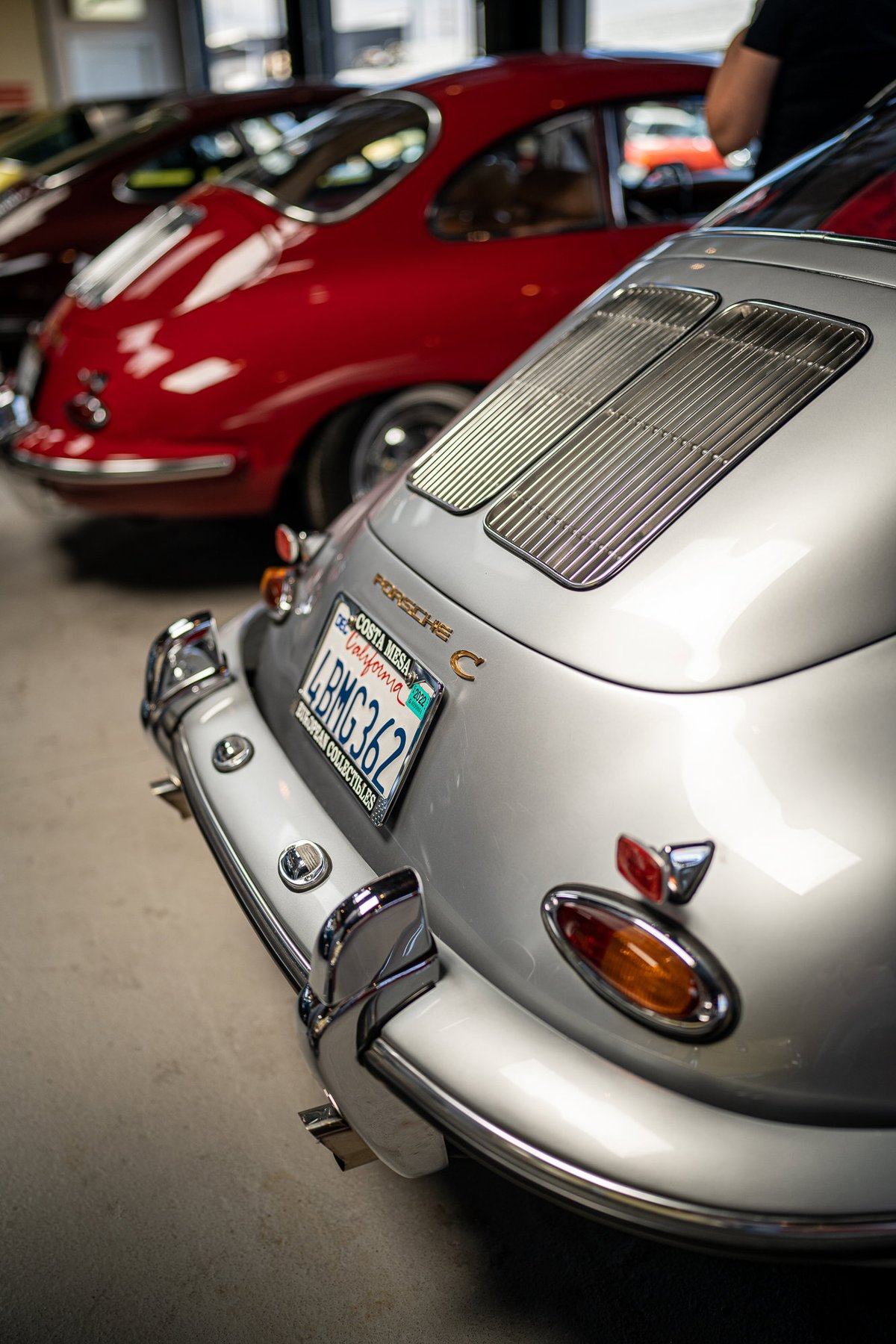 Rear view of a silver Porsche 356 C with chrome bumpers and louvered decklid.