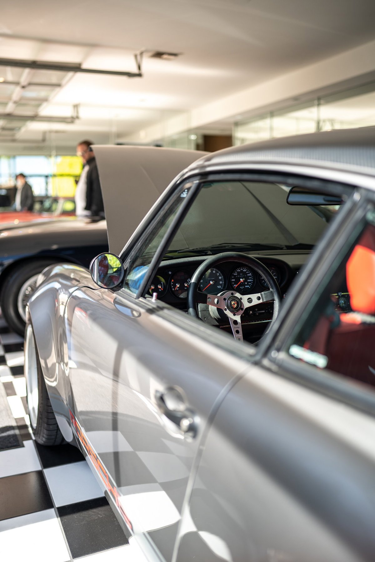 Silver Porsche 911 with racing livery, custom steering wheel, and racing seats.