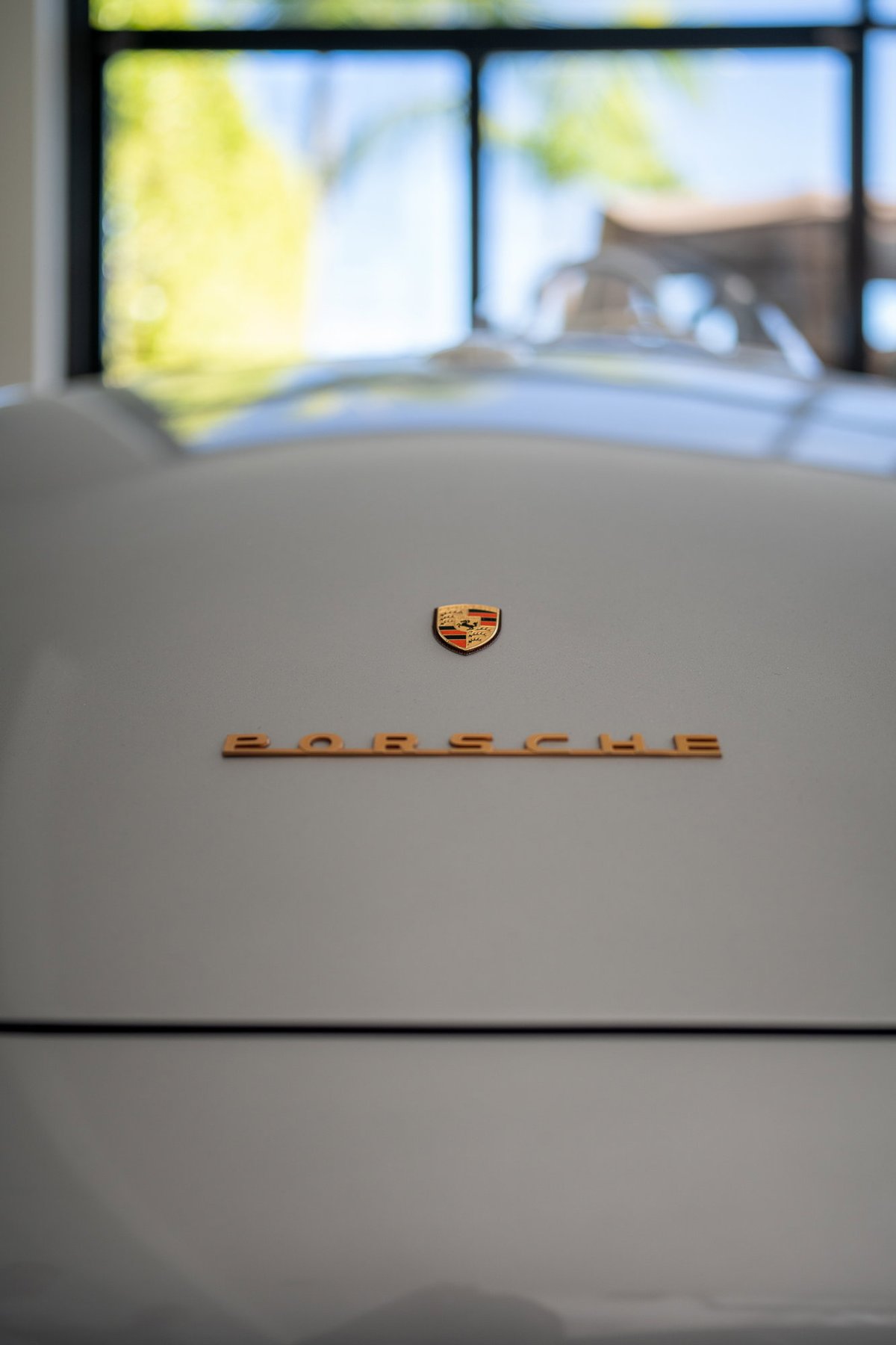 Close-up on a silver Porsche crest and "PORSCHE" script on the rear of the car.