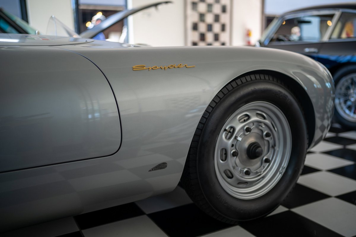 Silver Porsche 550 Spyder with gold badging and vintage steel rims.