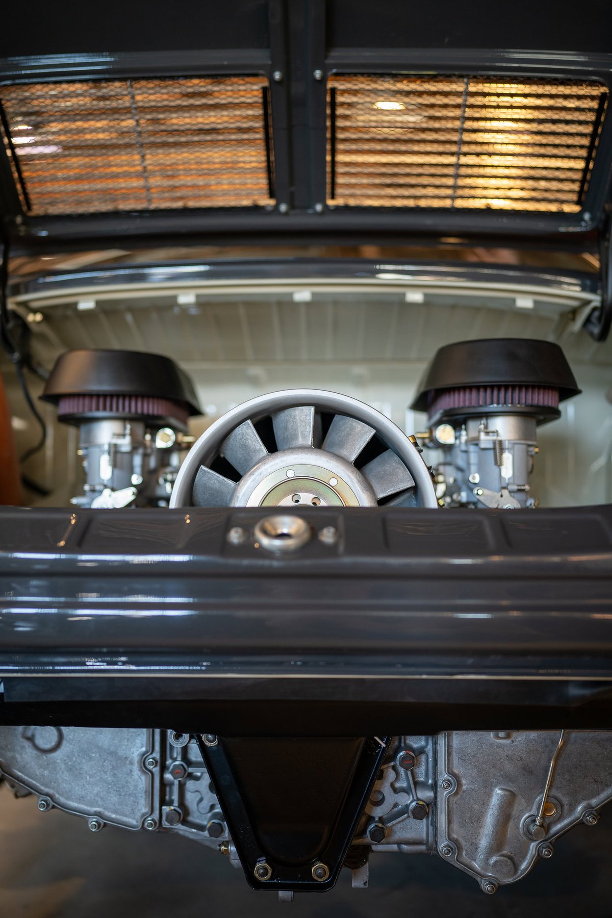 Porsche 911 engine bay with dual carburetors and cooling fan.