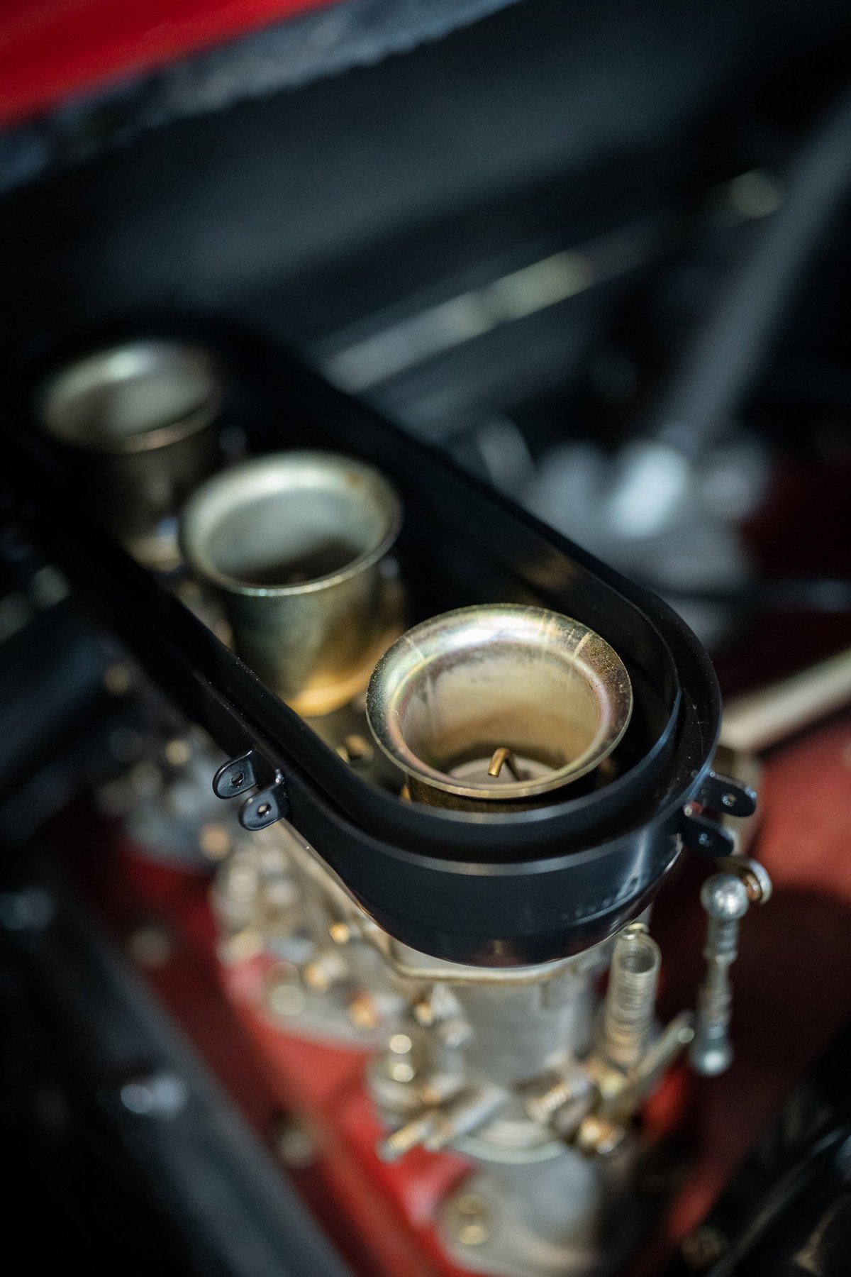 Vintage Ferrari V12 engine with triple Weber carburetors and velocity stacks. Red livery trim.