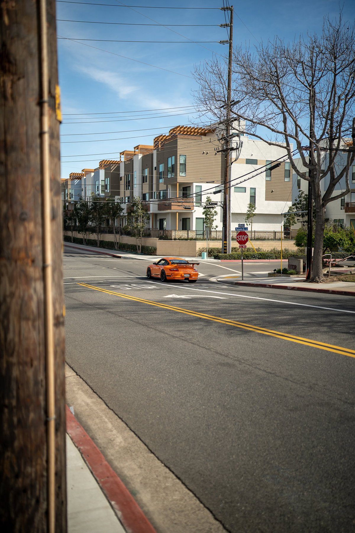 Orange Porsche 911 GT3 touring on street, featuring a prominent rear wing and black trim.