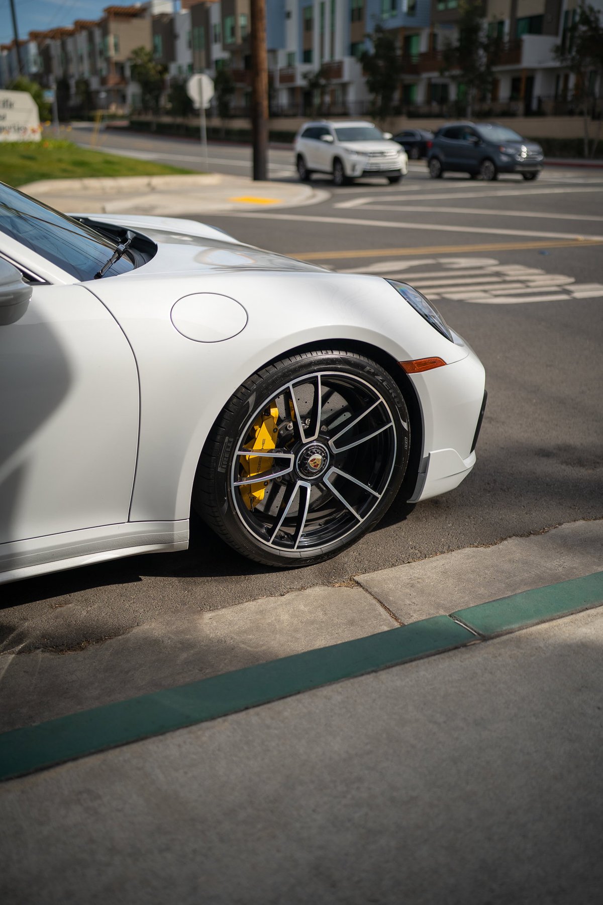 White Porsche 911 Carrera S with black alloy rims and yellow brake calipers.
