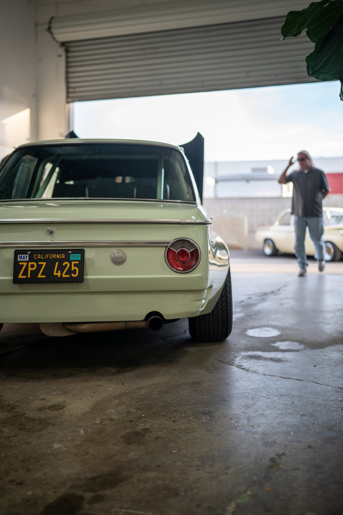 Pale green BMW 2002 with chrome trim and classic California plates.
