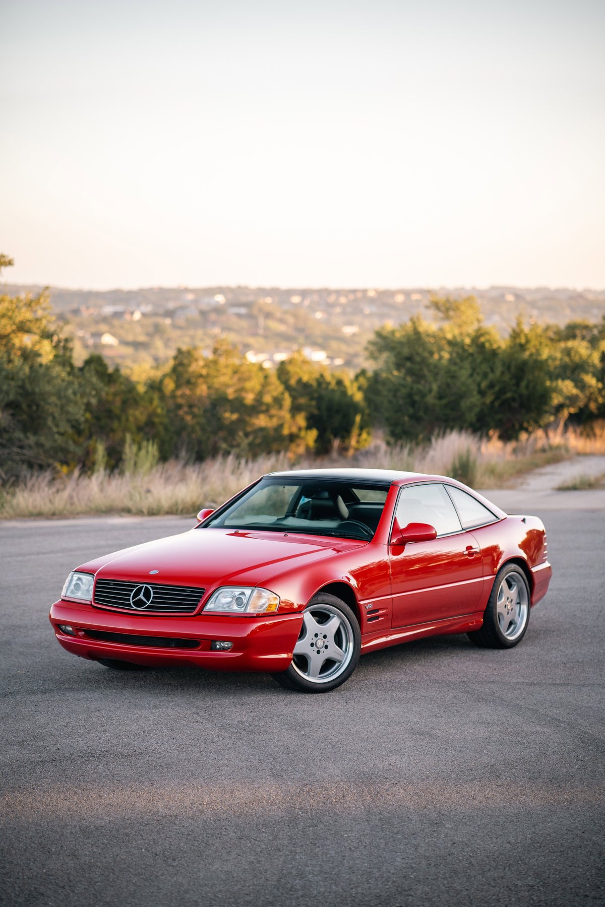 A red 2001 Mercedes-Benz SL600 with chrome rims parked on asphalt.