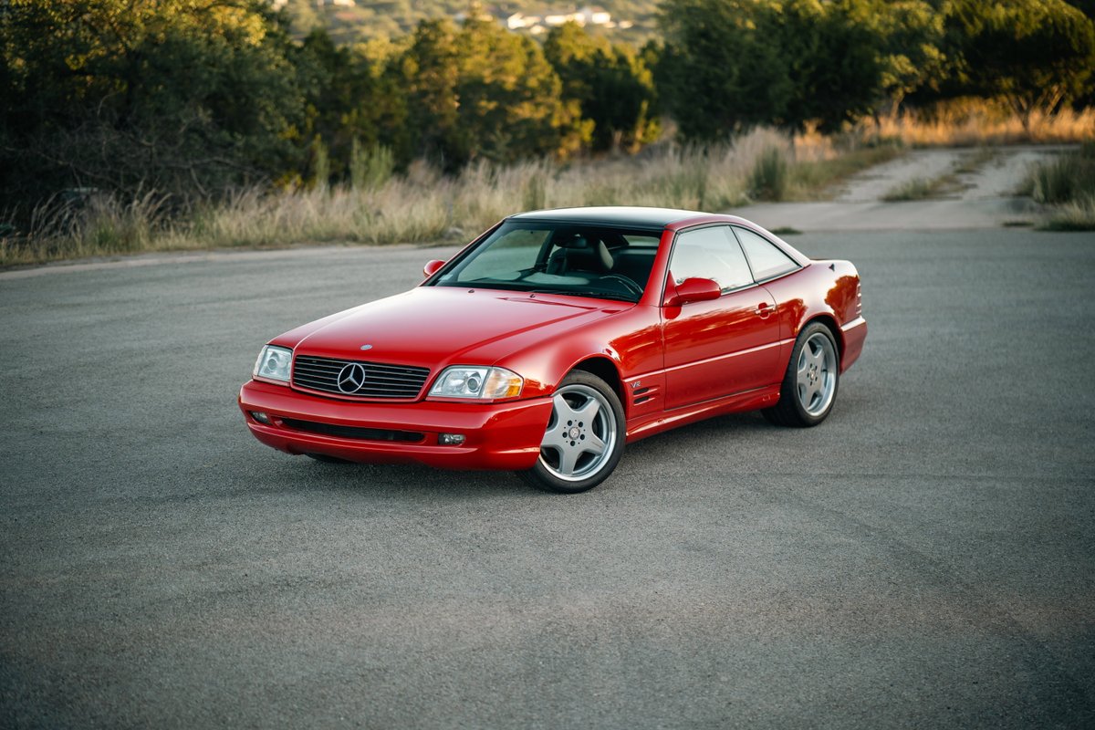 Red 2001 Mercedes-Benz SL600 coupe with chrome multi-spoke rims on pavement.