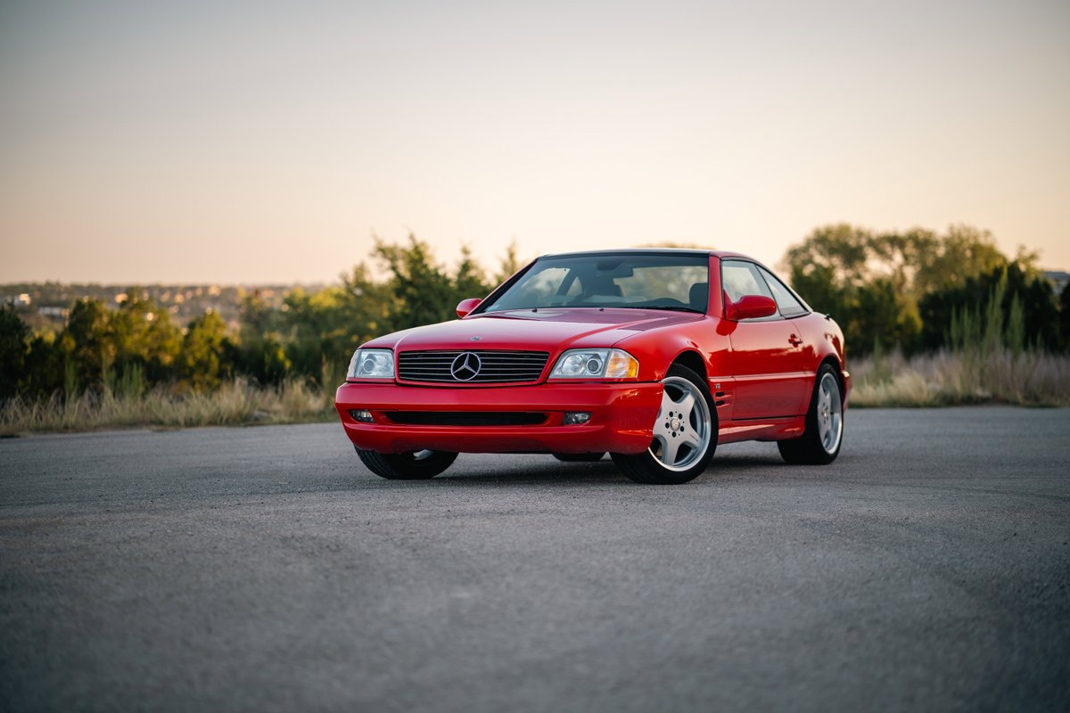 Red 2001 Mercedes-Benz SL600 with chrome alloy rims parked on asphalt.