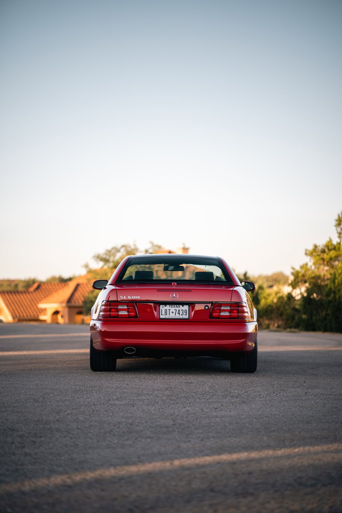Red 2001 Mercedes-Benz SL600 rear view with clear tail lights and chrome trim.