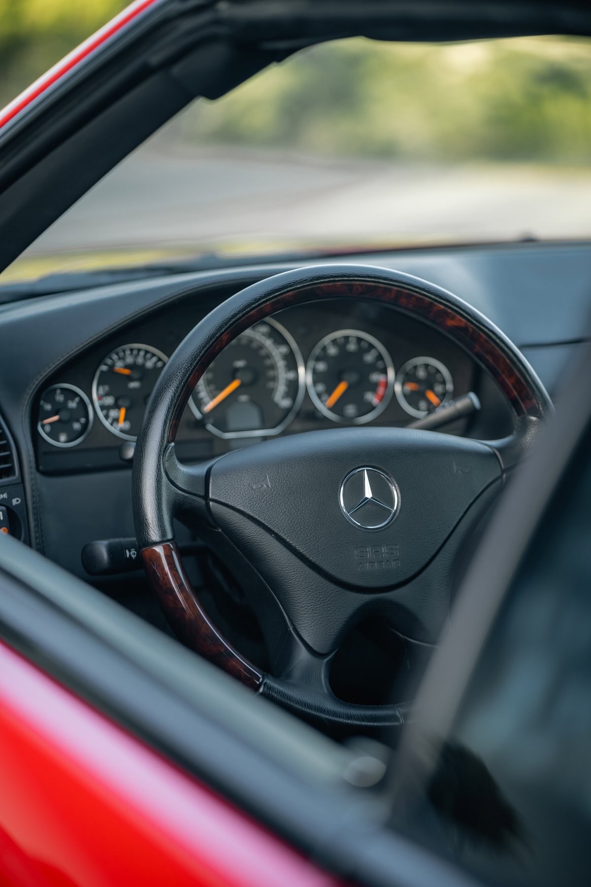Close-up of a 2001 Mercedes-Benz SL600 steering wheel with wood trim and Mercedes-Benz logo.
