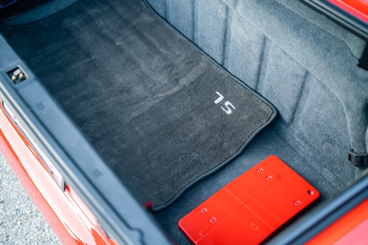 Trunk of a red 2001 Mercedes-Benz SL600 with a gray floor mat and red tool kit.