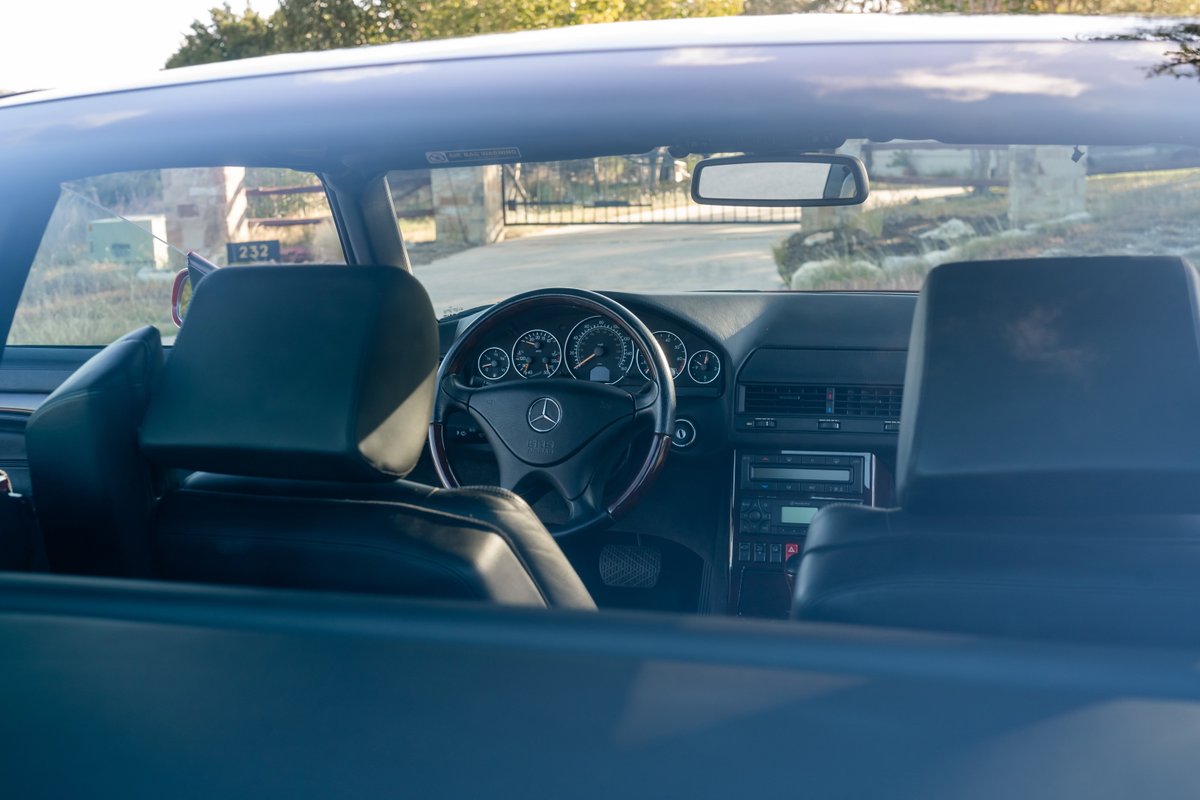 Interior view of a Magna Red 2001 Mercedes-Benz SL600, showing dashboard, steering wheel, and seats.