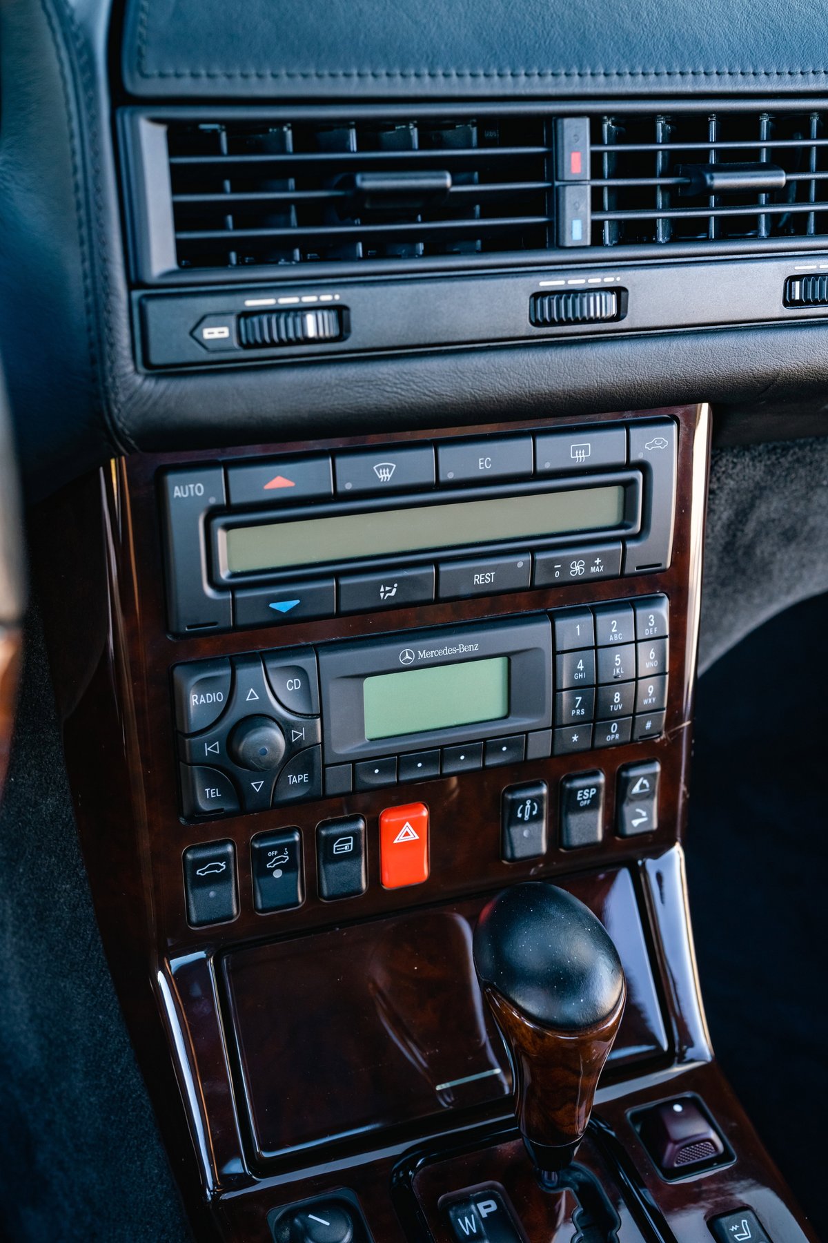 Close-up of the wood-trimmed Mercedes-Benz SL600 infotainment system with radio, CD, and climate controls.