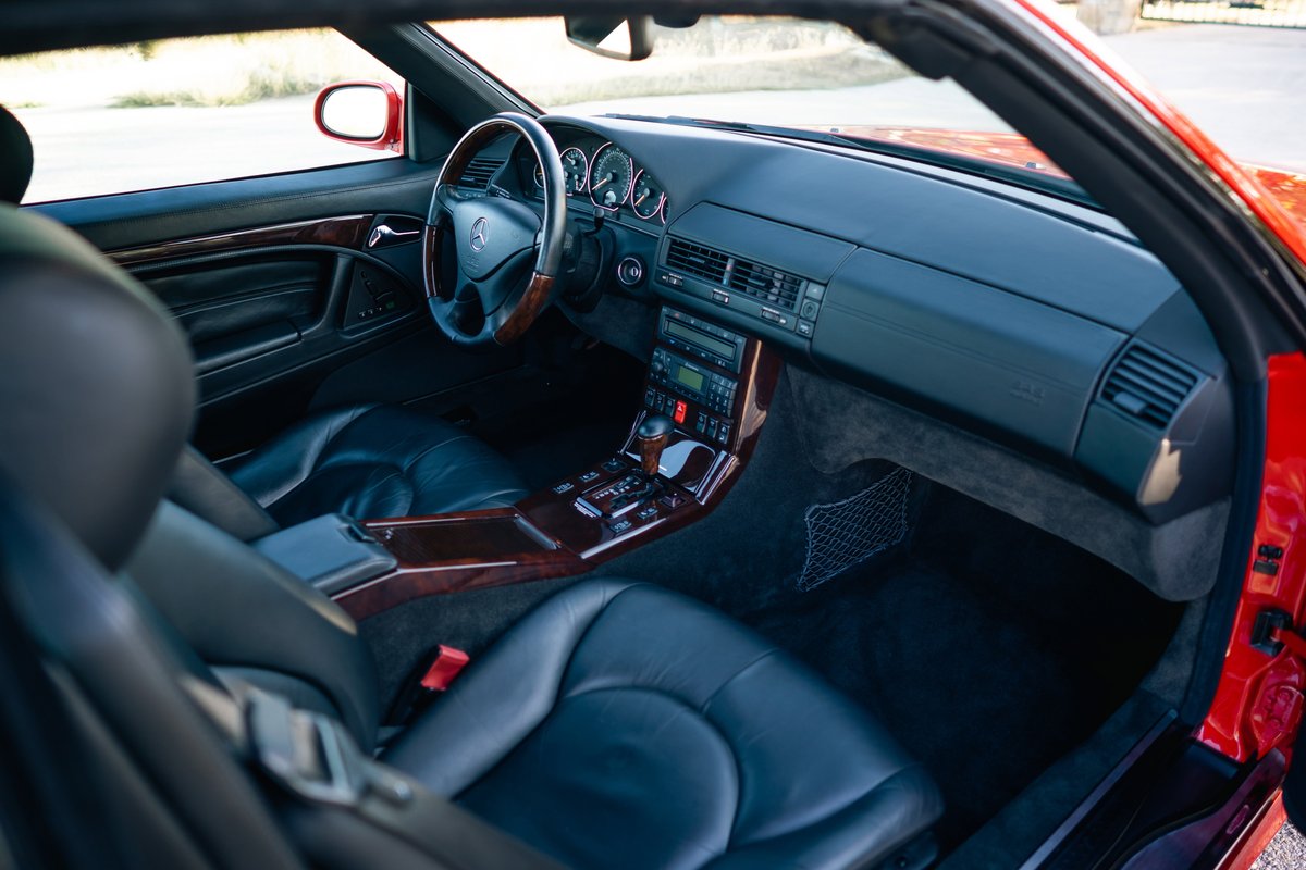 Interior of a red 2001 Mercedes-Benz SL600, featuring leather seats, wood trim, and a multimedia system.
