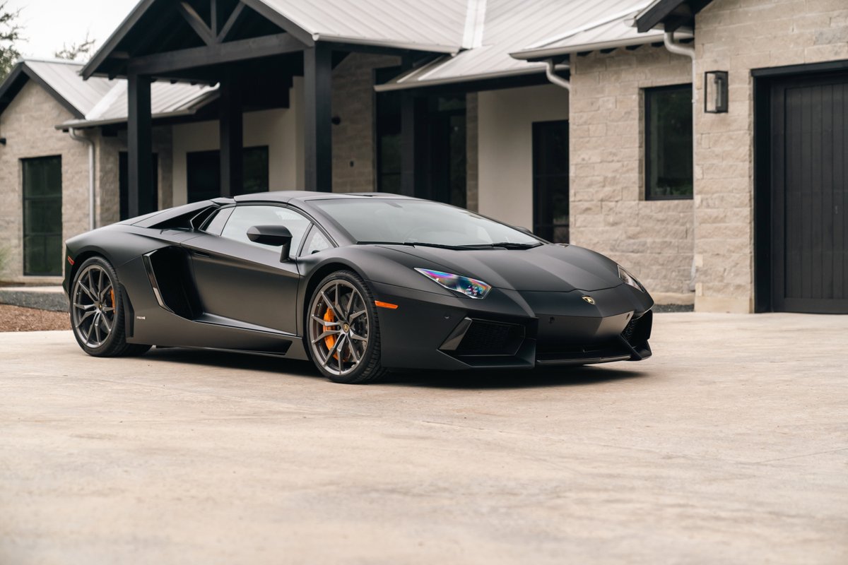 Matte black 2014 Lamborghini Aventador LP700-4 with orange brake calipers and multi-spoke rims.