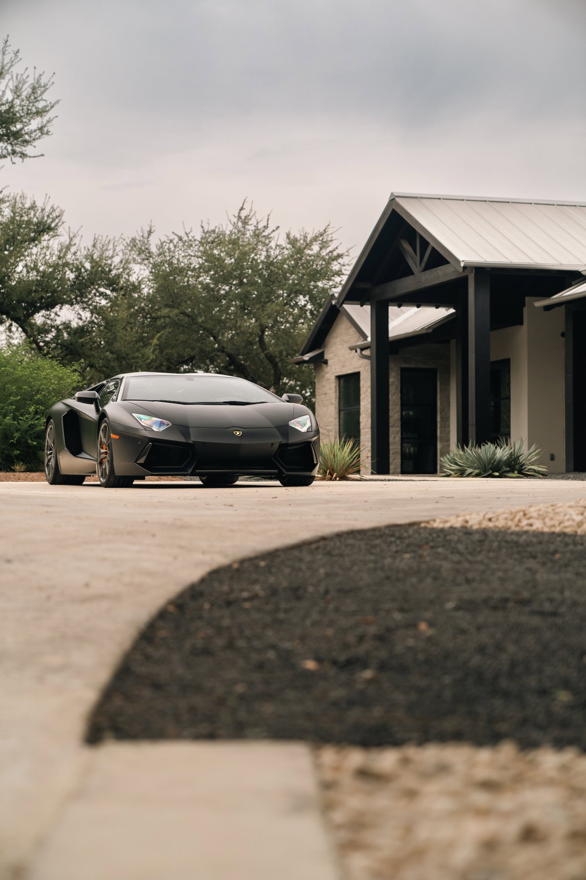 Matte black Lamborghini Aventador LP700-4 parked in a driveway.