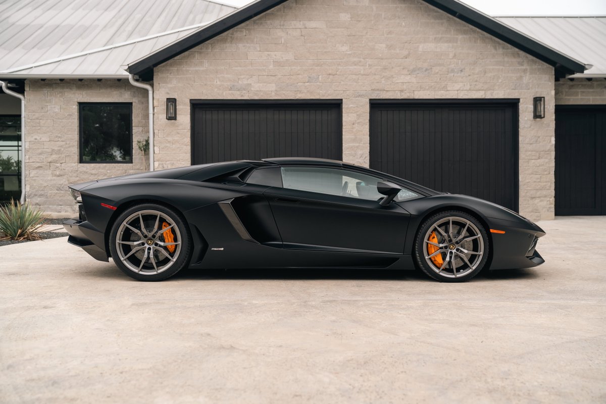 Matte black Lamborghini Aventador LP700-4 with gray rims and orange brake calipers.