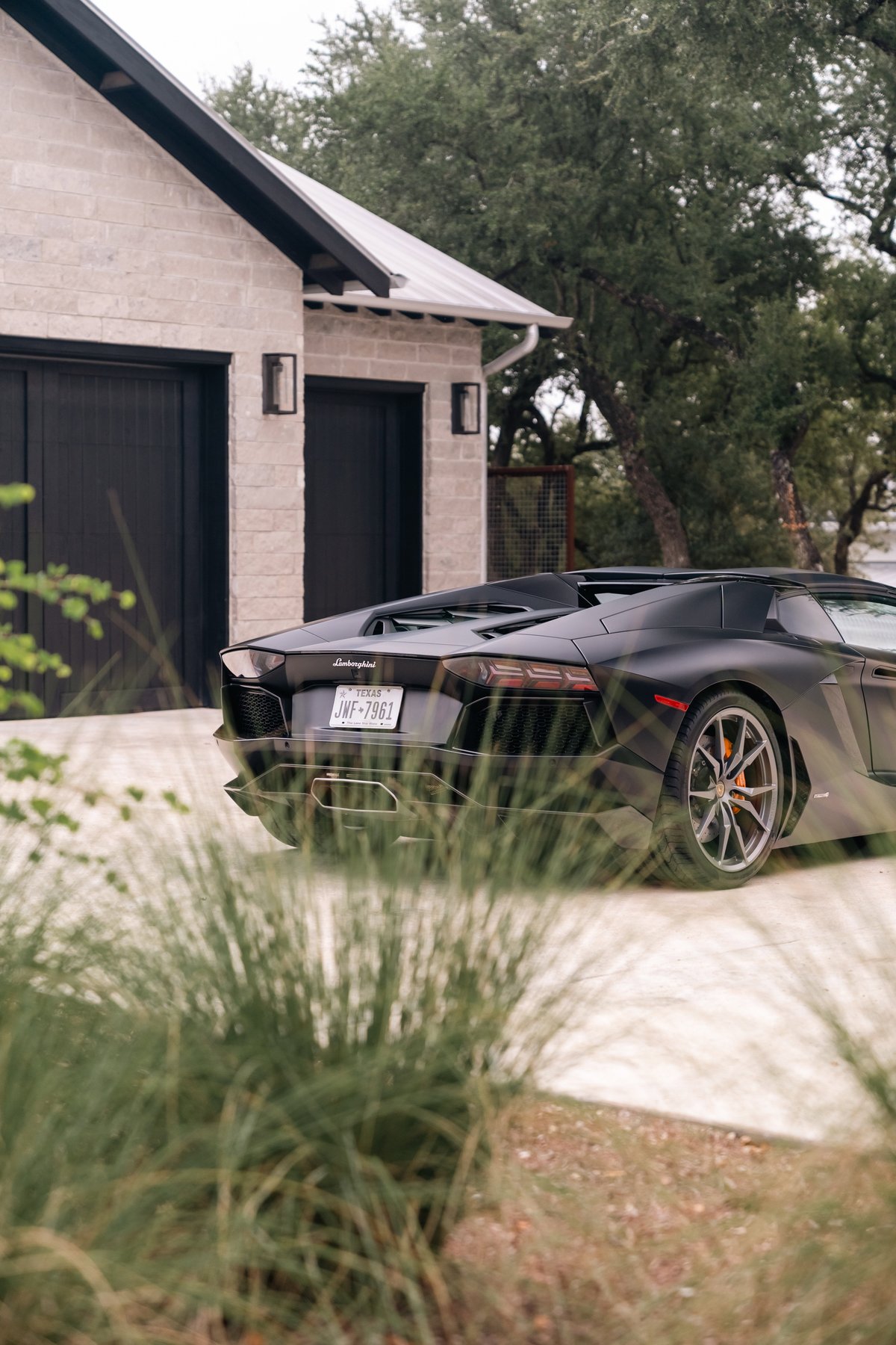 Black Lamborghini Aventador LP700-4 rear-view showing its multi-spoke rims and aggressive styling.