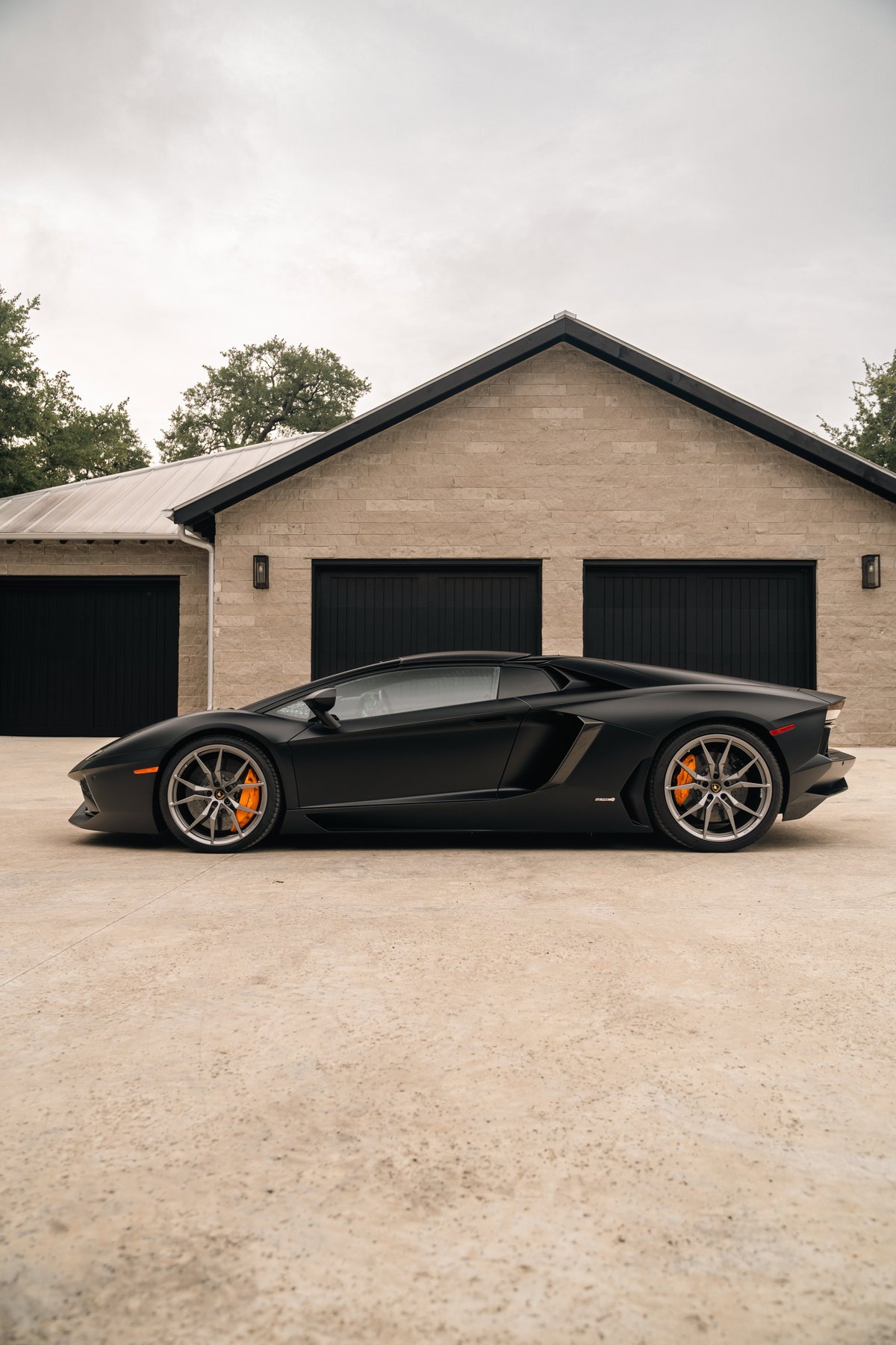Matte black Lamborghini Aventador LP700-4 with silver rims and orange brake calipers.