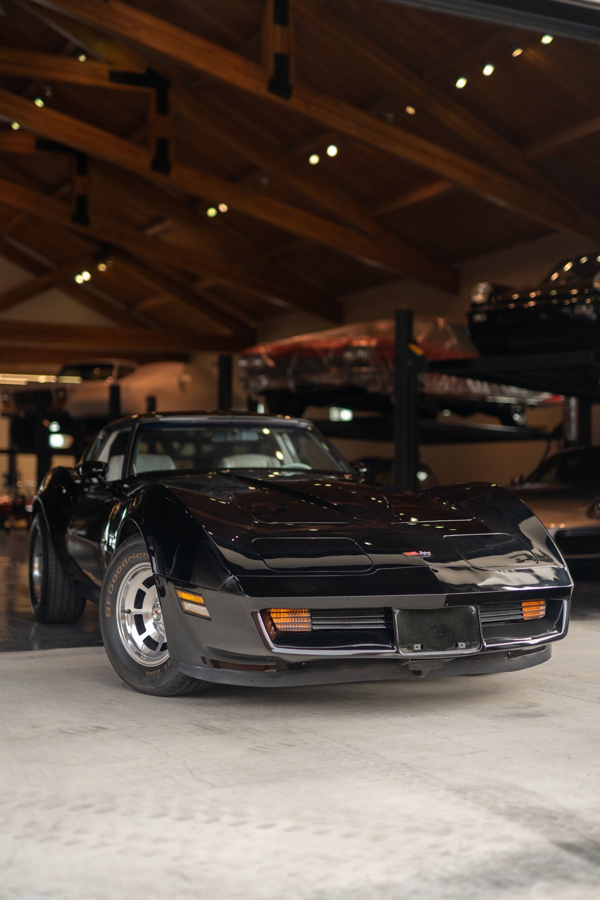Black 1982 Chevrolet Corvette Stingray coupe with alloy rims and T-tops.